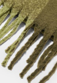 Olivengrøn tørklæde med frynser i enderne. Fremstillet af blødt, tekstureret materiale med kontrasterende nuancer af grøn for visuel interesse.