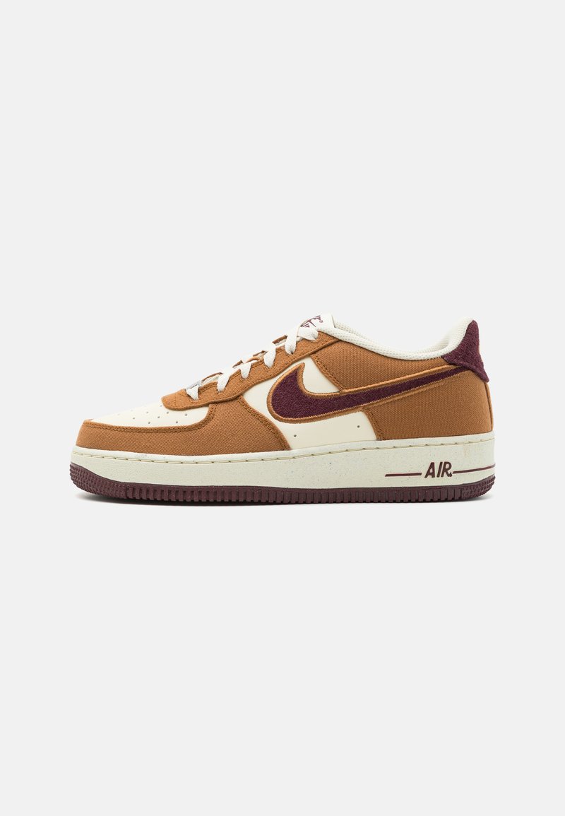 Sapatilhas castanhas e creme com materiais de camurça e lona. Apresentam um swoosh da Nike em borgonha, sola texturizada e a marca "AIR" no calcanhar.
