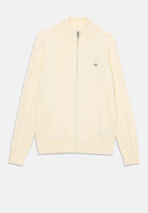 Světlekrémový svetr s kapsami a zipem, vyrobený z pleteniny, s žebrovaným límcem, manžetami a spodním lemem, obsahující malé vyšívané logo na levé hrudi.