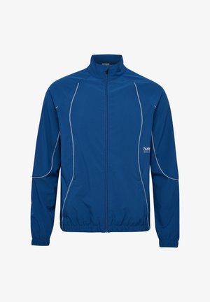 Blå idrottsjacka med dragkedja, hög krage och elastiska ärmslut. Har kontrasterande vita sid sömmar och en flexibel tygkonstruktion.