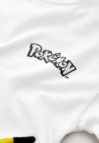 Weißes Baumwoll-T-Shirt mit einem schwarzen "Pokémon"-Logo. Der Stoff ist glatt und hat ein Rundhalsdesign mit kurzen Ärmeln.