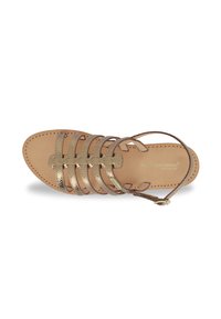 Open-toe sandal with a tan leather sole, featuring metallic gold straps and a delicate ankle strap. Stitched accents along the edges.