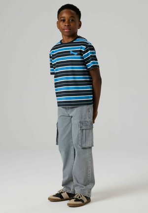 Plava i crna prugasta majica kratkih rukava, sive cargo hlače s džepovima i crne tenisice s bež detaljima.