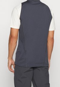 Camiseta atlética de manga corta con un respaldo gris oscuro, mangas gris claro y costuras en contraste, con una textura de tela suave y elástica.