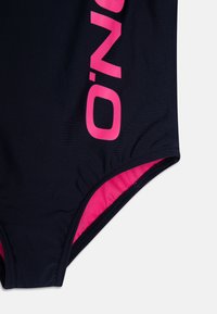 Maillot de bain bleu marine avec un grand logo rose, texture lisse et bordures roses contrastantes aux ouvertures des jambes.