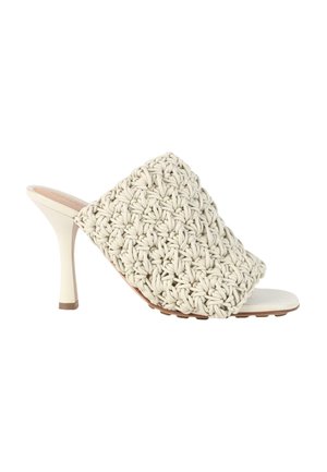 Mule beige à talon haut avec une large bride tissée et un talon fin et effilé sur fond blanc.