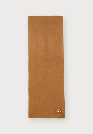 Cachecol castanho tricotado, feito de material suave, com um rótulo na parte de baixo com acentos circulares brancos e pretos.