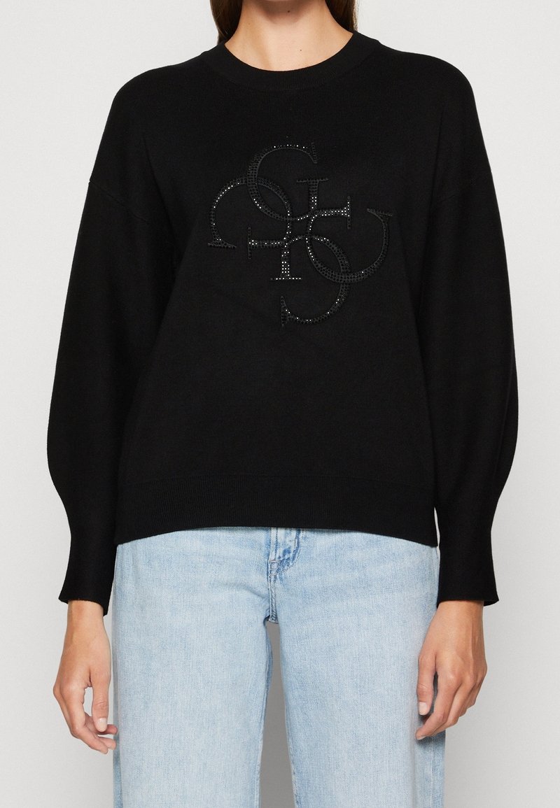 Black knitted pullover with a round neckline and balloon sleeves, featuring a textured logo in the center embellished with crystals.