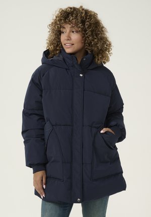Veste matelassée bleu marine avec capuche, présentant un design matelassé, des poches avant et une fermeture à pressions. Matière douce et résistante aux intempéries.