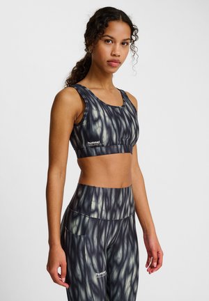 Atletische set met een fitted cropped tanktop en high-waisted leggings in een donkere stof met een zwirlpatroon. Merklogo gedrukt op de stukken.