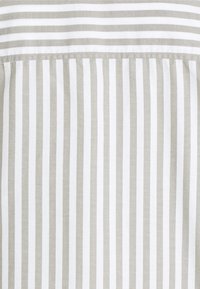 Tissu rayé avec des lignes verticales fines alternant gris et blanc. Texture lisse, matériau en coton, avec un design propre et moderne.