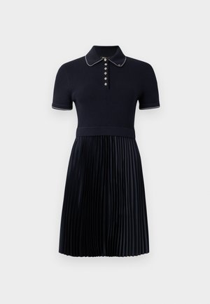 Navy blue polo dress with a ribbed top and pleated skirt. Features a classic collar, five-button placket, and subtle white accents.