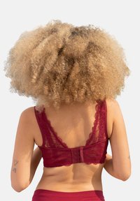 Burgunderfarbener Spitzen-Bralette mit gewellten Kanten, verstellbaren Trägern und einem Haken- und Ösenverschluss, der ein transparentes Rückendesign aufweist.
