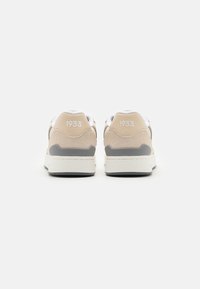 Beige sneakers med semsket finish, grå accenter og en hvit såle. Har "1933" preget på hælen. Rund design, glatte teksturer.