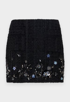 Mini saia de tweed preta com tecido texturizado, dois bolsos frontais e bordados florais decorativos com contas e lantejoulas ao longo da barra.