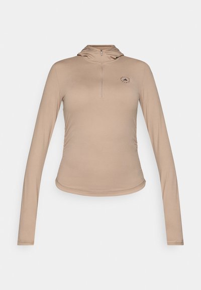 Beige long-sleeve top with a half-zip collar. Made from smooth fabric, featuring a small black logo on the chest and fitted design.