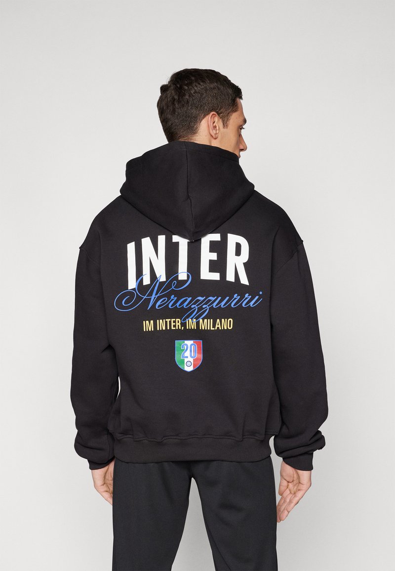 Sweatshirt preta com grandes letras brancas a dizer "INTER", com "Nerazzurri" em azul. Os detalhes incluem um escudo gráfico com "20" e cores italianas.
