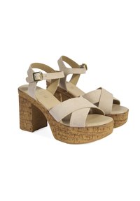 Sandales à talons hauts en suède beige avec des talons en liège, dotées de brides croisées et d'une boucle réglable à la cheville.