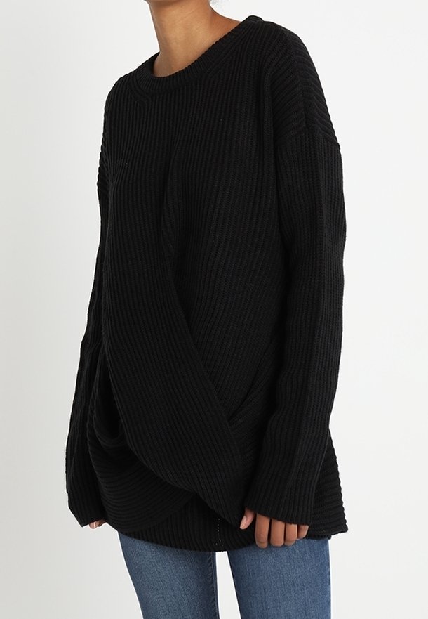 Pull en maille côtelée noir avec une coupe ample, épaules tombantes et manches longues. Possède une texture douce et un drapé subtil à l'ourlet.
