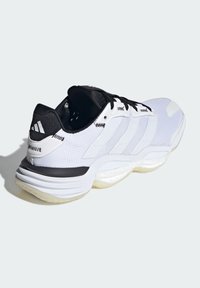 Zapatilla deportiva blanca con detalles negros, parte superior de malla y tres rayas blancas. Presenta una suela acolchada y agarre texturizado.