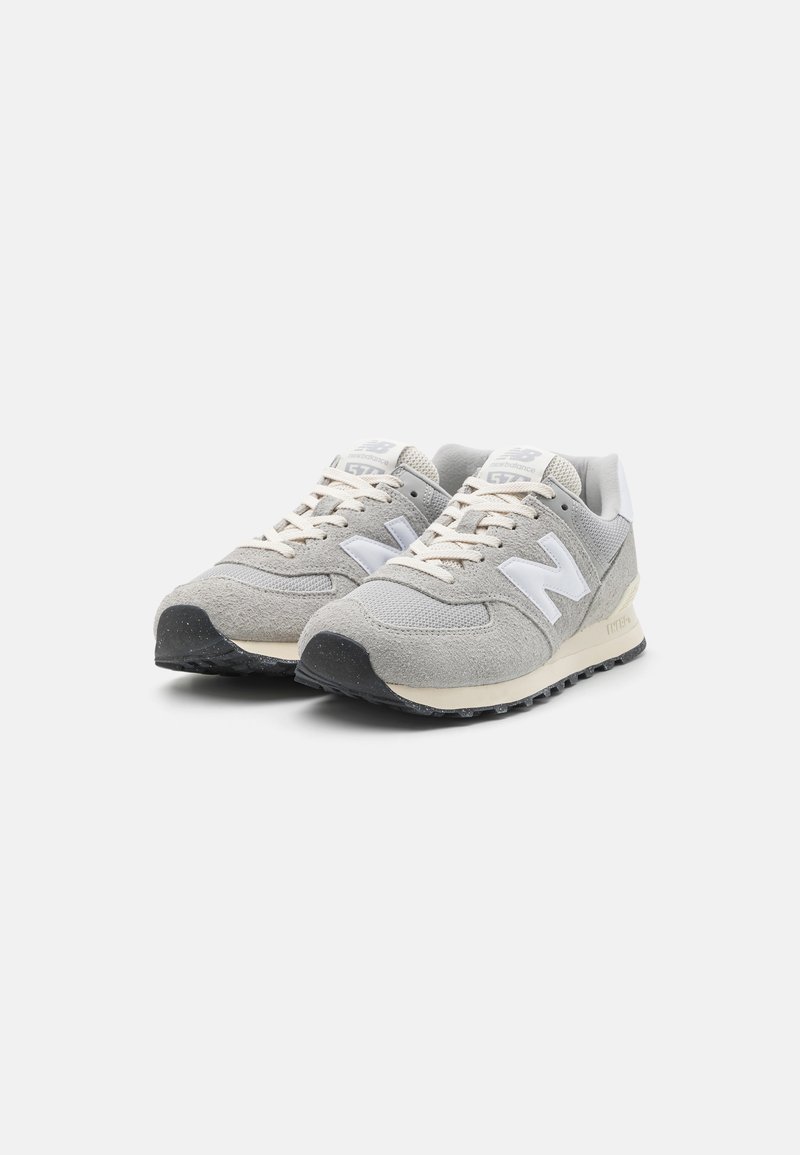 Helle graue Wildleder- und Mesh-Sneaker mit weißen Akzenten, runder Zehenpartie, flacher schwarzer Laufsohle und beiger Zwischensohle. Die Schnürsenkel sind hellbeige.