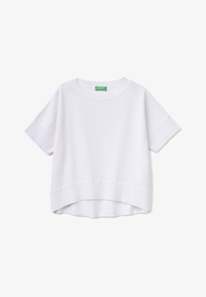 Top de punto blanco de manga corta con cuello redondo, puños y dobladillo acanalados, con una parte trasera ligeramente más larga y una etiqueta de marca verde en el interior del cuello.