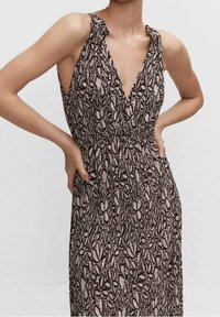 Robe maxi en noir et crème avec un motif floral, featuring un décolleté en V profond, sans manches et en tissu texturé. Détail de col ajustable.