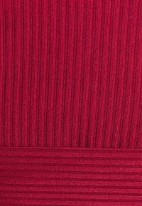 Tecido ribado em vermelho profundo com ligeiro brilho; riscas verticais variáveis criam textura. Acento horizontal suave na base.