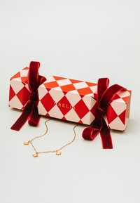 Crvene i ružičaste poklon kutije sa uzorkom dijamanta, ukrašene crvenim baršunastim trakama, unutar kojih se nalazi zlatni necklace sa zvjezdicom na svijetloj pozadini.