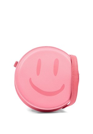 Sac bandoulière rond en cuir rose avec un discret motif de visage souriant rose plus foncé sur le devant et une sangle assortie.