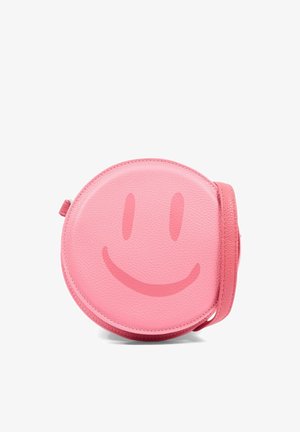 Ronde roze leren crossbodytas met een subtiel donkerder roze smiley-gezich ontwerp aan de voorkant en een bijpassende riem.