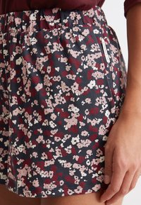 Bloemenprint shorts in donker marineblauw, met roze en witte bloemen. Elastische tailleband voor comfort, met een zijzak en een merketiket.