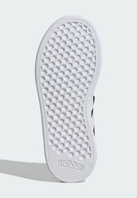 Bílá gumová podrážka boty s hexagonálním vzorem, s texturovaným gripem a vyraženým logem "adidas" na spodním okraji.
