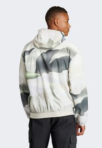 Lightweight hoodie in a camo pattern with gray, white, and green hues. Features a drawstring hood and elastic hem for a snug fit.