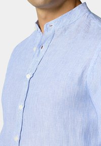 Světle modrá pruhovaná košile s mandarínkovým límcem, bílé knoflíky, texturovaná látka a přiléhavý střih.