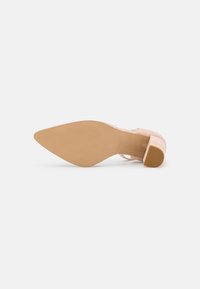 Blush pink high-heeled shoe with a textured upper, a pointed toe, and a chunky tan heel, viewed from the sole.