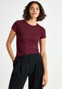 Rød og sort stribet t-shirt med korte ærmer og rund halsudskæring, parret med sorte højtaljede bukser med en afslappet pasform.