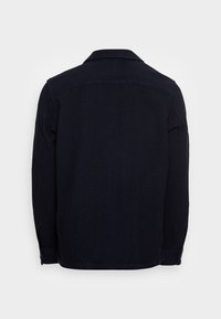 Giacca blu scuro con colletto, maniche lunghe e polsini abbottonati. Presenta una texture semplice e un orlo dritto nella parte inferiore.