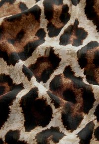 Tkanina w leopardzi wzór z miękką, teksturowaną powierzchnią w odcieniach brązu, kremu i czerni, o płynnej, układającej się formie.