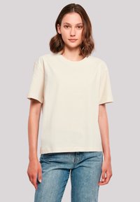 Cremfarbene Baumwoll-T-Shirt mit Rundhalsausschnitt und kurzen Ärmeln, mit einem lockeren Schnitt und glatter Textur. Getragen mit hellblauen Jeans.