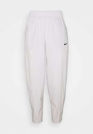Białe spodnie dresowe Nike z elastycznym paskiem, zwężanymi nogawkami i małym czarnym logo Nike swoosh na górnej części lewego uda.