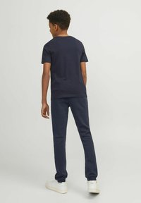 Marine blauwe katoen t-shirt en sweatpants set, met een relaxte pasvorm en geribbelde halslijn. De schoenen zijn wit met een gestructureerde zool.