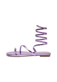 Sandal flat metallico viola con più cinghie sottili e un avvolgimento a spirale attorno alla caviglia. Texture liscia, design minimalista e suola piatta.