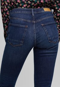 Mörkblå denimjeans med en figurnära design. Funktioner inkluderar två bakfickor, diskret sömnad och en slät yta.