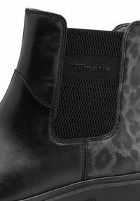 Botín negro hasta el tobillo con cuero liso y paneles laterales elásticos. Presenta un acento de estampado animal texturizado y un detalle de marca sutil.