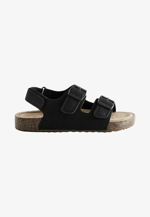 Sort sandal med åben tå med to justerbare stropper og spænder på toppen, en ankelrem med velcro og en korkmønstret sål.