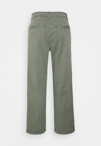 Olijfgroene canvasbroek met een rechte pasvorm, voorzien van twee achterzakken en een eenvoudige tailleband, die een schone, gladde textuur toont.