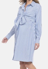 Sukienka w paski w niebiesko-białym kolorze, z detalem w postaci wiązania w talii, długimi rękawami i luźnym krojem. Wykonana z bawełnianej tkaniny o gładkiej fakturze.