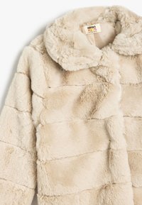 Cremefarbener Kunstpelzmantel mit einem geschichteten Design, Druckknopfverschlüssen und einem runden Kragen. Weicher Textur mit dezenten Farbvariationen.