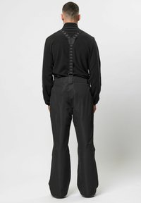 Zwarte waterdichte skibroek met verstelbare bretels. Kenmerkt zich door brede, uitlopende pijpen en een soepele textuur, die een functioneel sportief ontwerp biedt.